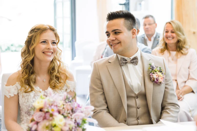 Der Bräutigam schaut seine Braut verliebt an, während sie nach vorne blickt. Eine ergreifende Szene der Trauung in Voshövel.