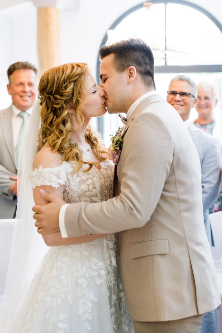 Braut und Bräutigam küssen sich innig bei ihrer Trauung im Confideum Voshövel.