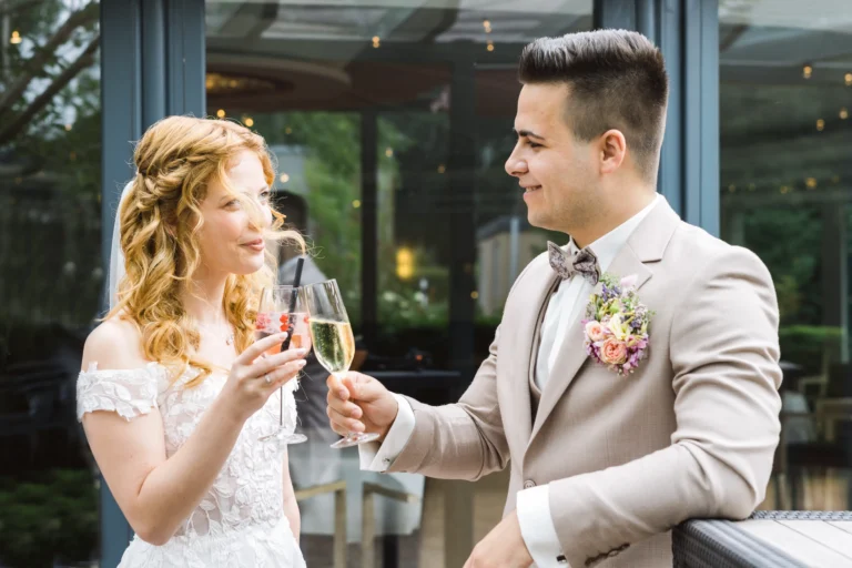 Braut und Bräutigam stoßen mit Champagner an während ihres Sektempfangs im Landhotel Voshövel