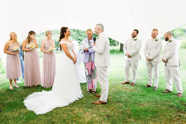 Braut und Bräutigam während der freien Trauung mit Brautjungfern und Groomsmen unter einem weißen Zeltdach – Hochzeitsfotograf Schloss Raesfeld.