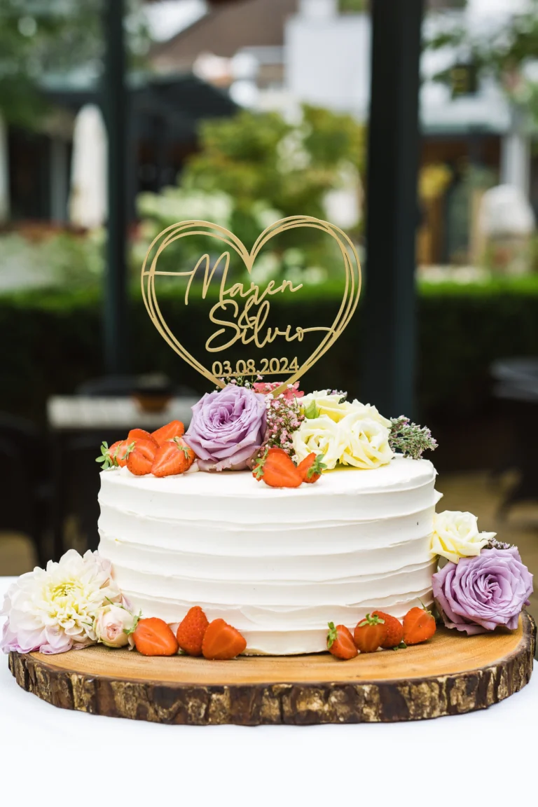Weiße Hochzeitstorte mit Herz-Topper und floraler Dekoration im Landhotel Voshövel