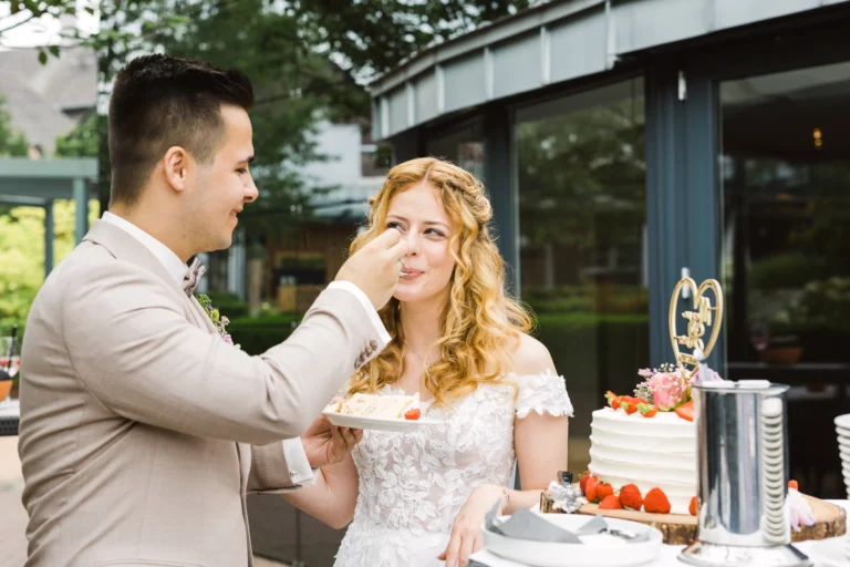 Bräutigam füttert Braut mit einem Stück Hochzeitstorte im Landhotel Voshövel
