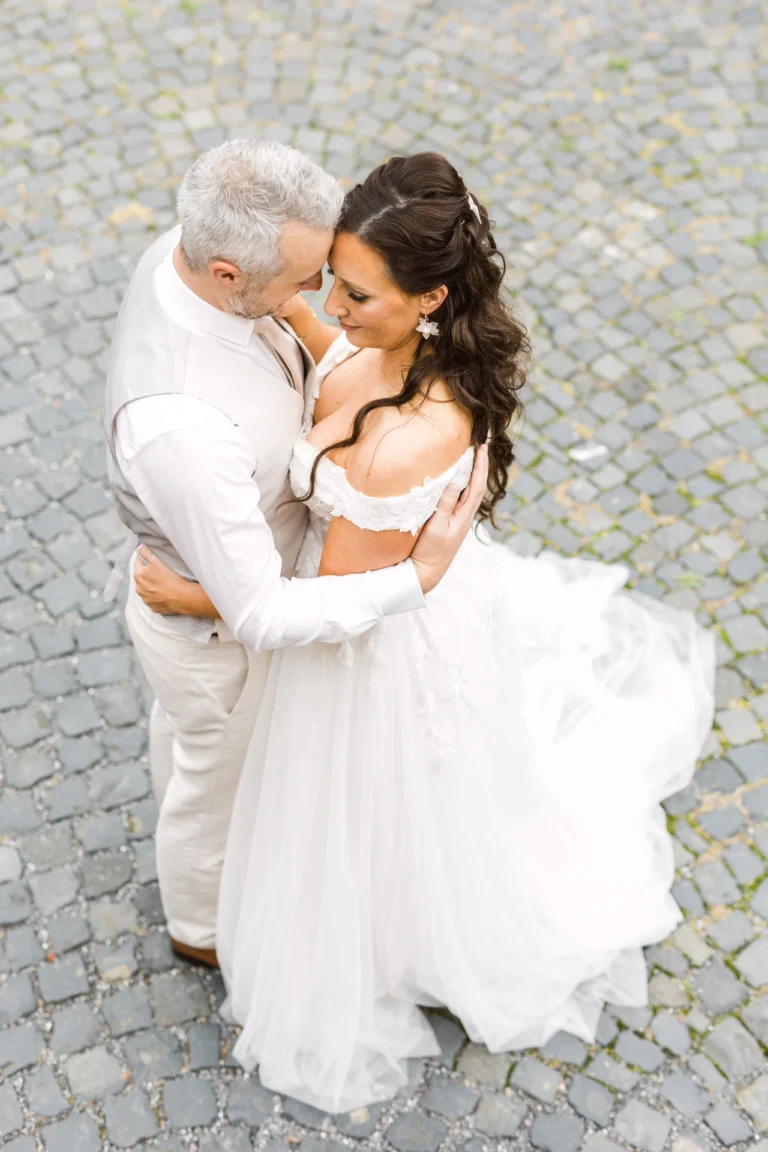 Vogelperspektive auf Braut und Bräutigam in inniger Umarmung auf Kopfsteinpflaster – Hochzeitsfotograf Schloss Raesfeld.