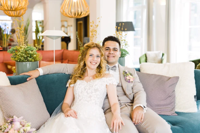 Braut und Bräutigam sitzen gemeinsam auf einer stilvollen Couch im Landhotel Voshövel Hochzeit – ein ruhiger Augenblick voller Glück und Verbundenheit.