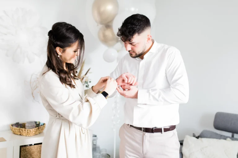 Ein Bräutigam bekommt von seiner Schwester Hilfe beim Anlegen der Manschettenknöpfe – elegantes Detail des Getting Ready.