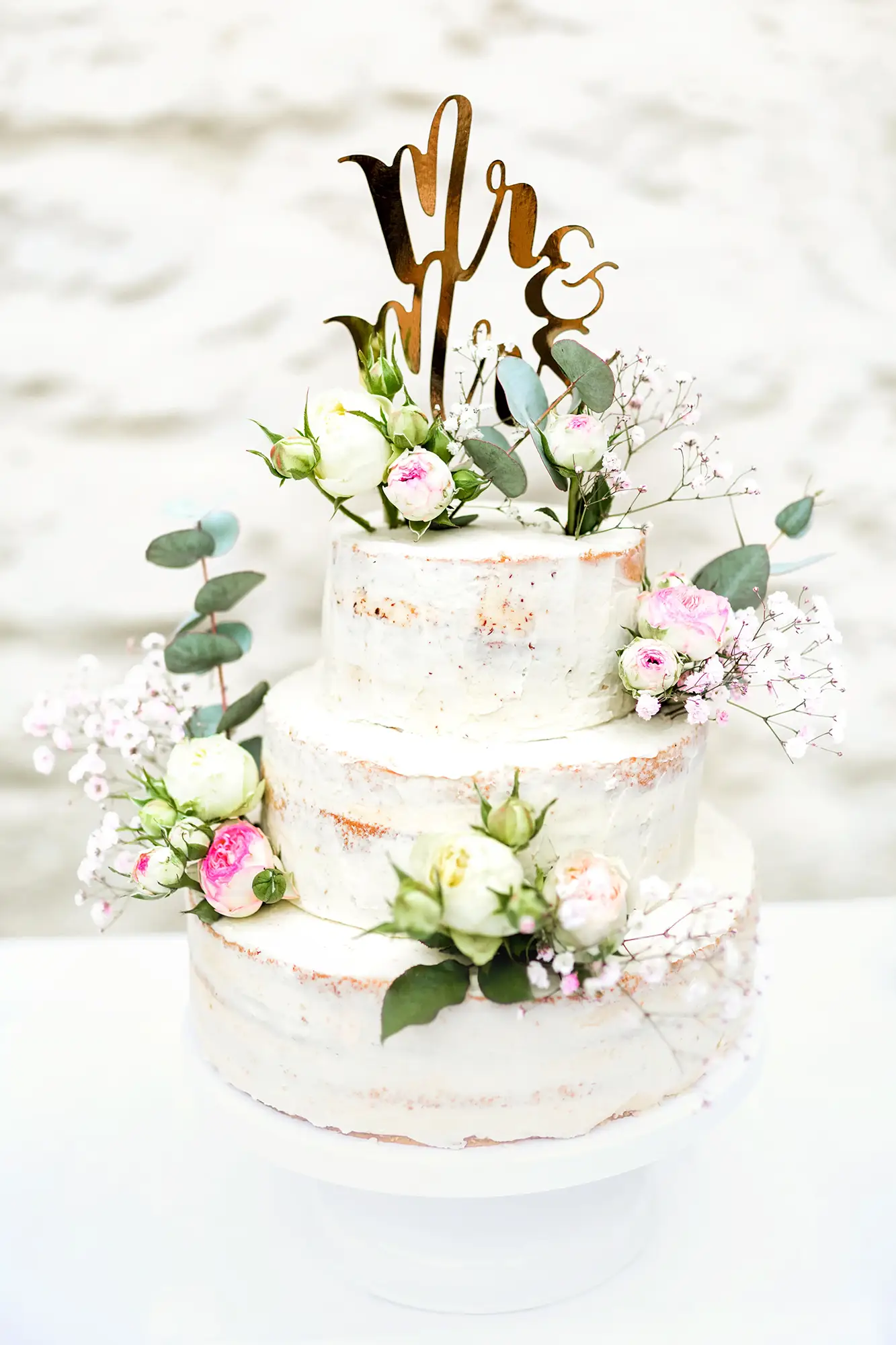 Dreistöckige Hochzeitstorte im Naked-Cake-Stil mit frischen Blumen dekoriert – fotografiert von einem Hochzeitsfotografen in NRW, Preise auf Anfrage