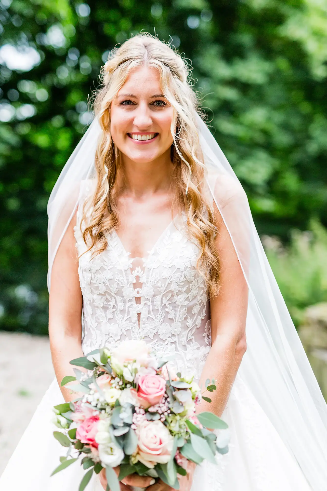 Glückliche Braut im Spitzenkleid mit romantischem Brautstrauß – Hochzeitsfotograf in Düsseldorf, Preise individuell anpassbar.